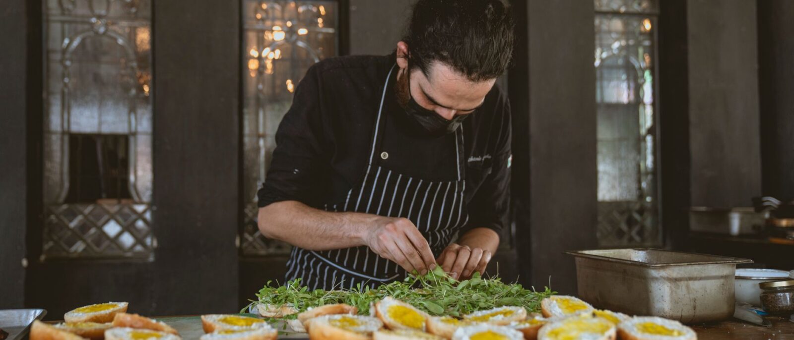 Chef concentra-se em preparar sanduíches gourmet com ingredientes frescos em um restaurante elegante
