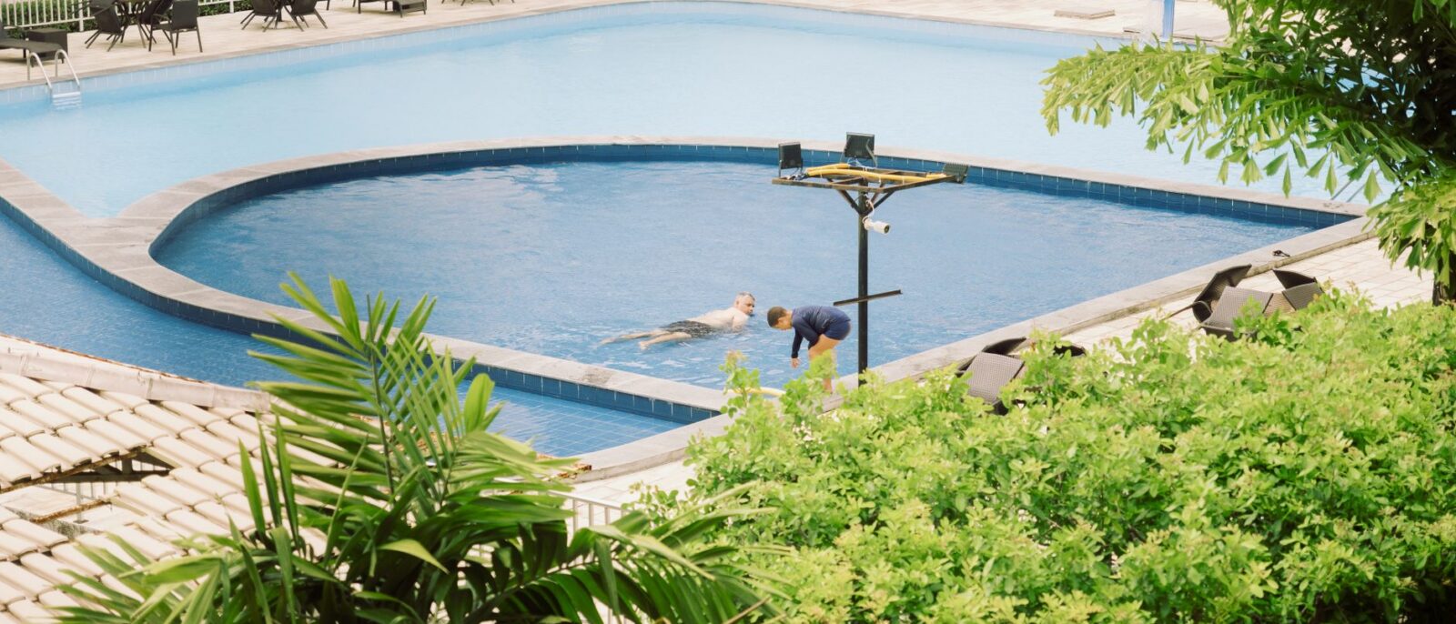 Uma cena tranquila com pessoas aproveitando um dia ensolarado à beira de uma piscina em Pernambuco, Brasil
