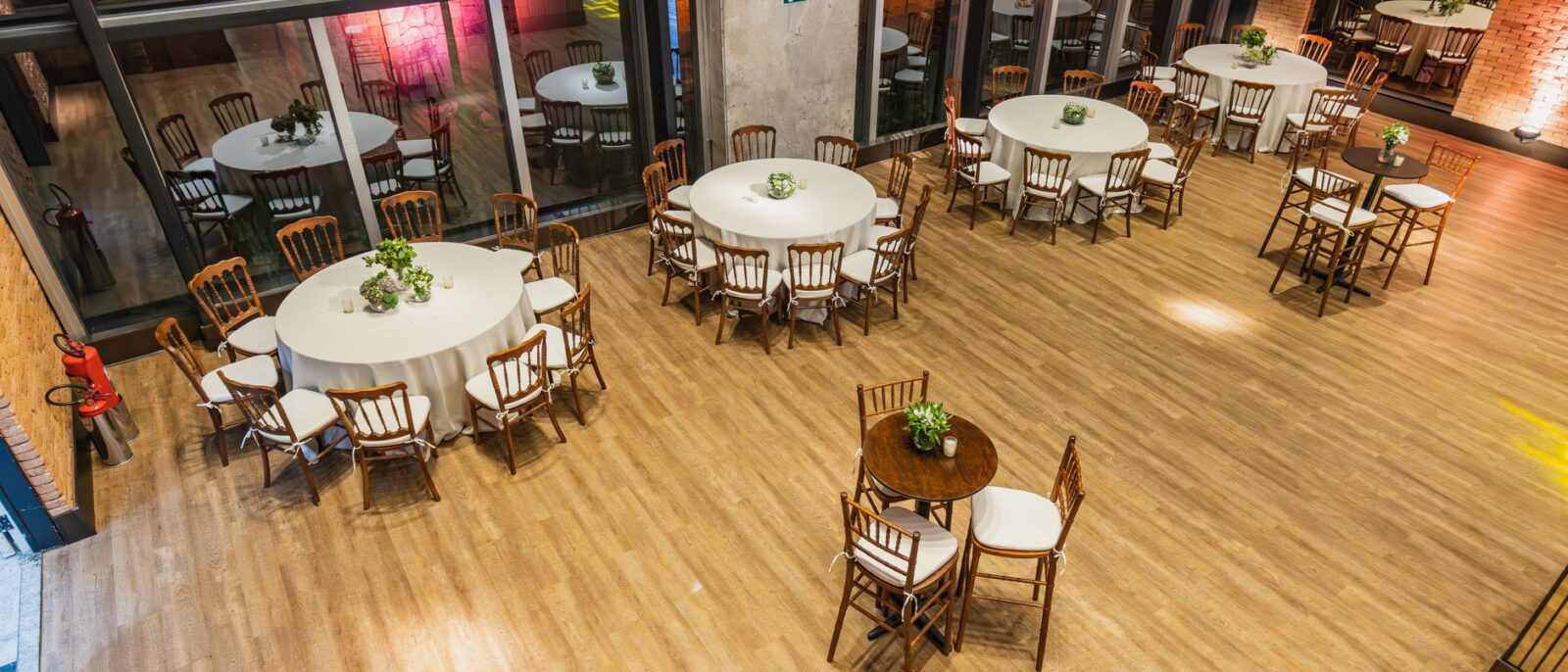 Amplo salão de eventos interno com mesas redondas e cadeiras elegantemente dispostas para ocasião especial