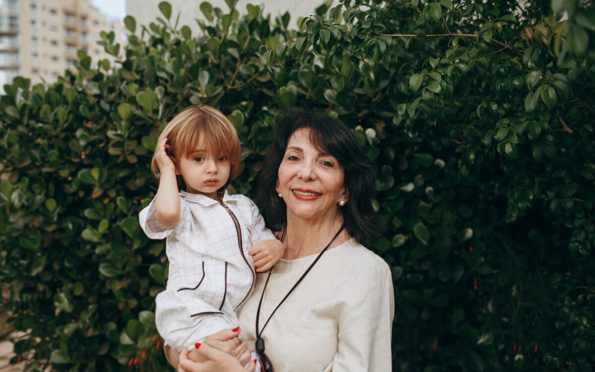 Uma avó carinhosa com sua neta sorrindo ao ar livre em um exuberante jardim