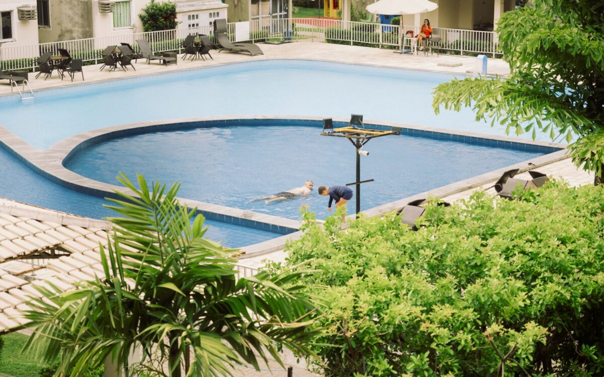 Uma cena tranquila com pessoas desfrutando de um dia ensolarado à beira da piscina em Pernambuco, Brasil